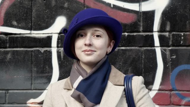 Pretty woman stand style hat city. Beautiful person in blue hat looking at camera with cheerful smile close up carefree face background graffiti wall 4K. Cute girl happy face glamour look flirt man.