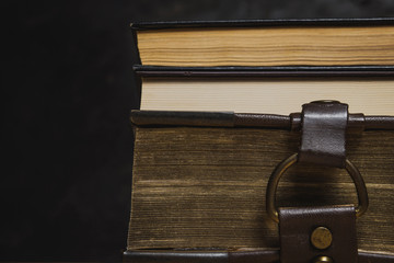 The concept of literature. Several old books are stacked on a dark background.