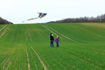 Children launch a kite in a field in spring