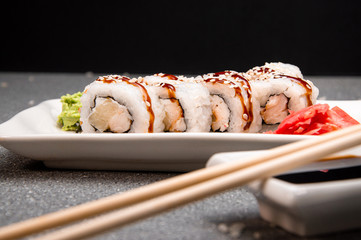 White rolls with sauce and sesame seeds. White cup. Red ginger