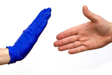 the chick of a man in a blue medical glove stops an unprotected hand trying to greet him