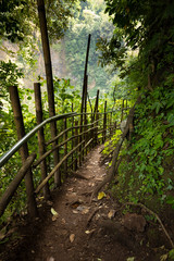Trail with bamboo fences and boards, heading towards the waterfall at Tumpak Sewu waterfall, in East Java, Indonesia.