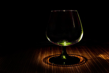 Crystal glass on a bamboo stand on a dark background © Дмитрий Кузнецов