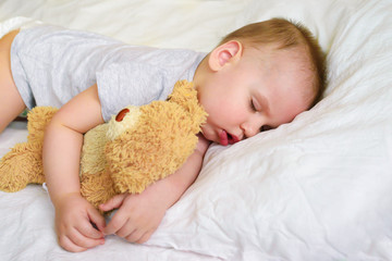 close-up portrait of a beautiful sleeping boy on a white bed background