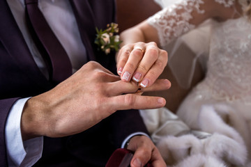 Obraz na płótnie Canvas bride puts a wedding ring on the groom's finger