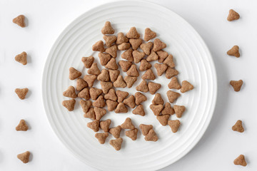 Domestic cat food. Minimalism top view flat lay plate with white dry food. Pet care.