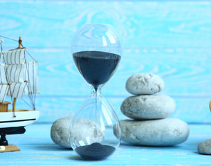 Banner with beach accessories on a blue board aquamarine color background - hourglass, boat, sea ​​stones. Summer. Concept of summer holidays. Vacation and Travel Time Concept.