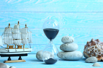 Banner with beach accessories on a blue board aquamarine color background - hourglass, boat, sea ​​stones. Summer. Concept of summer holidays. Vacation and Travel Time Concept.