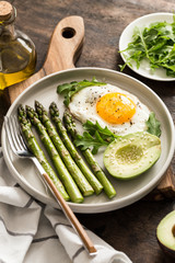 Healthy homemade breakfast with asparagus, fried egg, avocado and arugula. quarantine healthy eating concept. keto diet