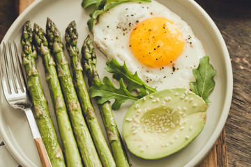 Healthy homemade breakfast with asparagus, fried egg, avocado and arugula. quarantine healthy eating concept. keto diet