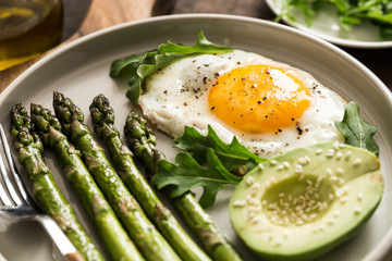Healthy homemade breakfast with asparagus, fried egg, avocado and arugula. quarantine healthy eating concept. keto diet