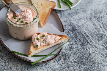 Salmon and soft creme cheese spread in jar. Salmon rillettes, mousse, pate and toasts on gray...