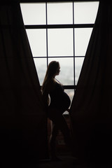 Pregnant women, photoshoot in dark key with black leather coat and hat
