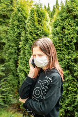 A teenage girl is talking on the phone in a mask filled with green trees