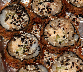 Fried sushi with sesame seeds. Sushi with cucumber, cheese, tuna and honey sauce.