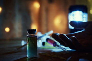 Drug overdose. The use of drugs leads to death. A bottle of heroin and a cocaine path near the hand...