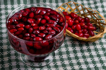 dogwood jam and next to it fresh dogwood in a wicker basket, all on a plaid towel