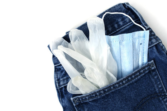 Classic blue jeans on the white background. Medical mask and gloves in the pocket. Pandemic concept. Copy space. Place for text and design. Top view. Flat layout