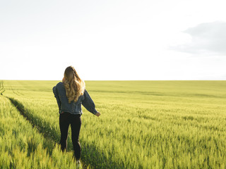 
Young blonde girl running through the green wheat field. Concept of travel, inspiration, freedom, lifestyle.