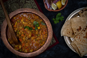 Indian mixed vegetables curry and flat breads on dark table