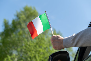 Man holding Italy flag from the open car window. Concept