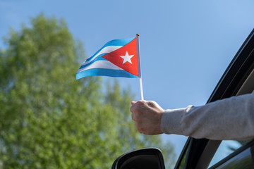 Man holding Cuba flag from the open car window. Concept