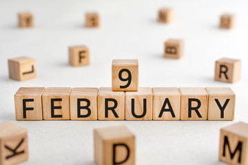 February 9 - from wooden blocks with letters, important date concept, white background random letters around