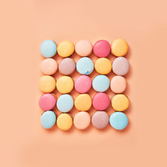 Macaroons on colored background, a lot of colorful french cookies macarons. Beige, brown french cookies macarons on  yellow peach background