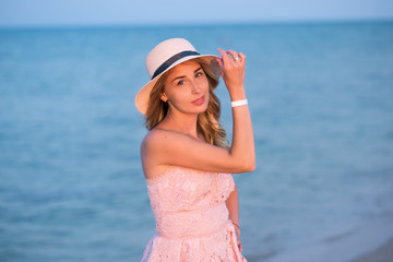 girl with a ball on the beach. young woman in hat on the beach. young woman in pink dress on the beach. 
Holidays at sea.