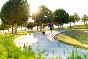 man wearing a protective mask is walking alone with a dog outdoors because of the corona virus pandemic covid-19