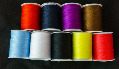 Multi-colored spools of thread close-up on a dark background.