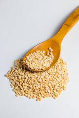a handful of peas and a wooden spoon above it. There are not so many peas on a spoon. Photo on a white background