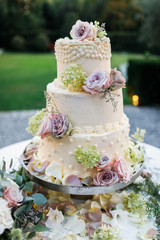Obraz na płótnie Canvas Wedding cake standing on the table. Around the flowers.