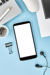 Vertical mockup image of a smartphone with blank white screen on blue surface. Flat lay