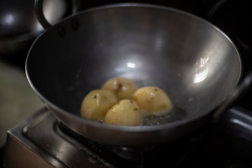 potatoes are fried in oil in a large cooking pot in an Indian kitchen. Indian food and kitchen.