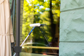 An employee washes a large stained-glass window of the store. Washes a shop window.