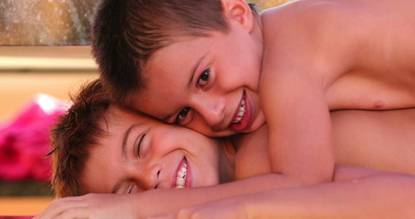 Funny moment together between brothers one child lying on top of sibling compressing body with...