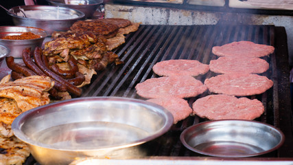 Grilling various types of meat. Preparation of burgers, sausages and meat at street. Burgers and buns on the grill. 