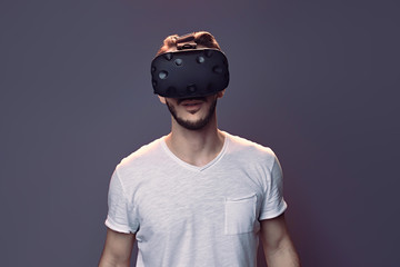 Technology, gaming, entertainment and people concept - Portret of amazed happy young smiling man enjoy with virtual reality headset or 3d glasses in studio isolated neon purple background close up © Pavel Shcherbakov