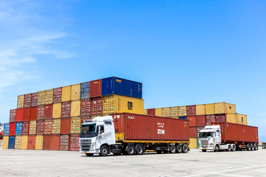 Shipping Containers in various colors stacked at a holding platform.