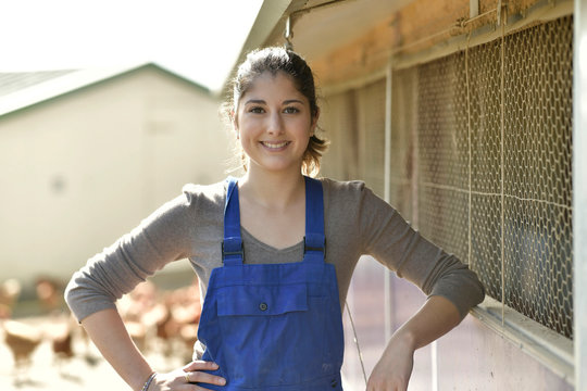 Smiling young farmer standing in poultry yard