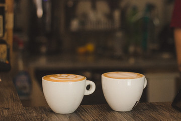A small white cup of coffee stands on table in coffee shop. Fragrant pressure. Background. Space for text. 