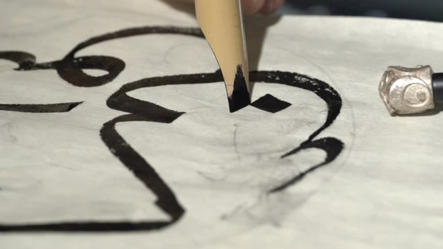 calligrapher writes arabic lettering with calligraphy pen on parchment. macro shot of islamic calligraphy art. close up slider dolly shot in calligrapher workshop. hand made calligraphy
