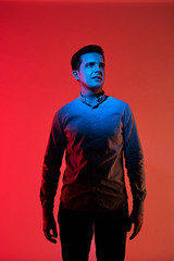 Fashion art portrait of pensive young guy face, looking away. Red and blue light color. Creative person, casual clothes. Creative сrisis and inspiration concept. Inspired, thinks of the great