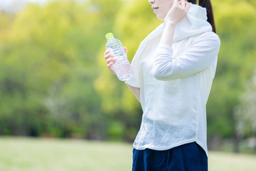 ペットボトルを持ち佇む運動着姿の若い女性