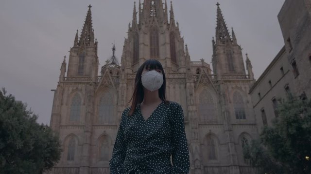In a pandemic emergency a japanese girl wears a mask in Barcelona city in front of Cathedral 4K