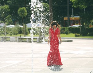 A beautiful young girl poses in an elegant red dress at her prom 