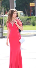 Fototapeta premium A beautiful young girl poses in an elegant red dress at her prom 