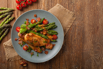 Roasted chicken breast, served on asparagus with tomato sauce, dried tomatoes. Top view.
