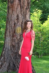 A beautiful young girl poses in an elegant red dress at her prom 